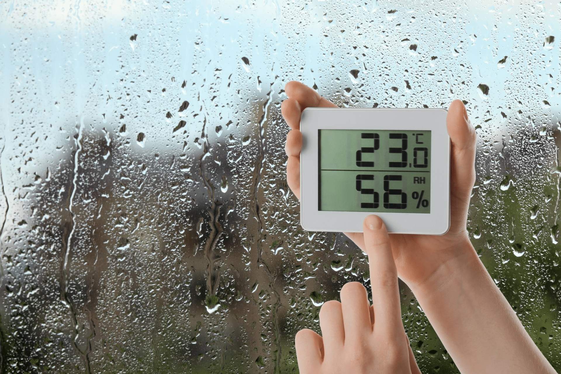 imagem de uma janela umida, é possível ver um termostato com a temperatura do ambiente e do porcentagem de umidade no ar.