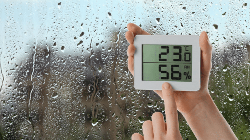 imagem de uma janela umida, é possível ver um termostato com a temperatura do ambiente e do porcentagem de umidade no ar.