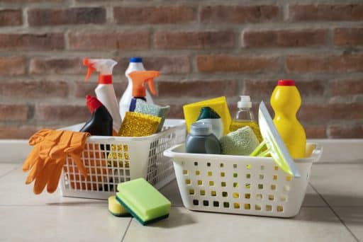Imagem de dois cestos cheios de produtos de limpeza, é possível ver acessórios como luvas, esponja e rodo